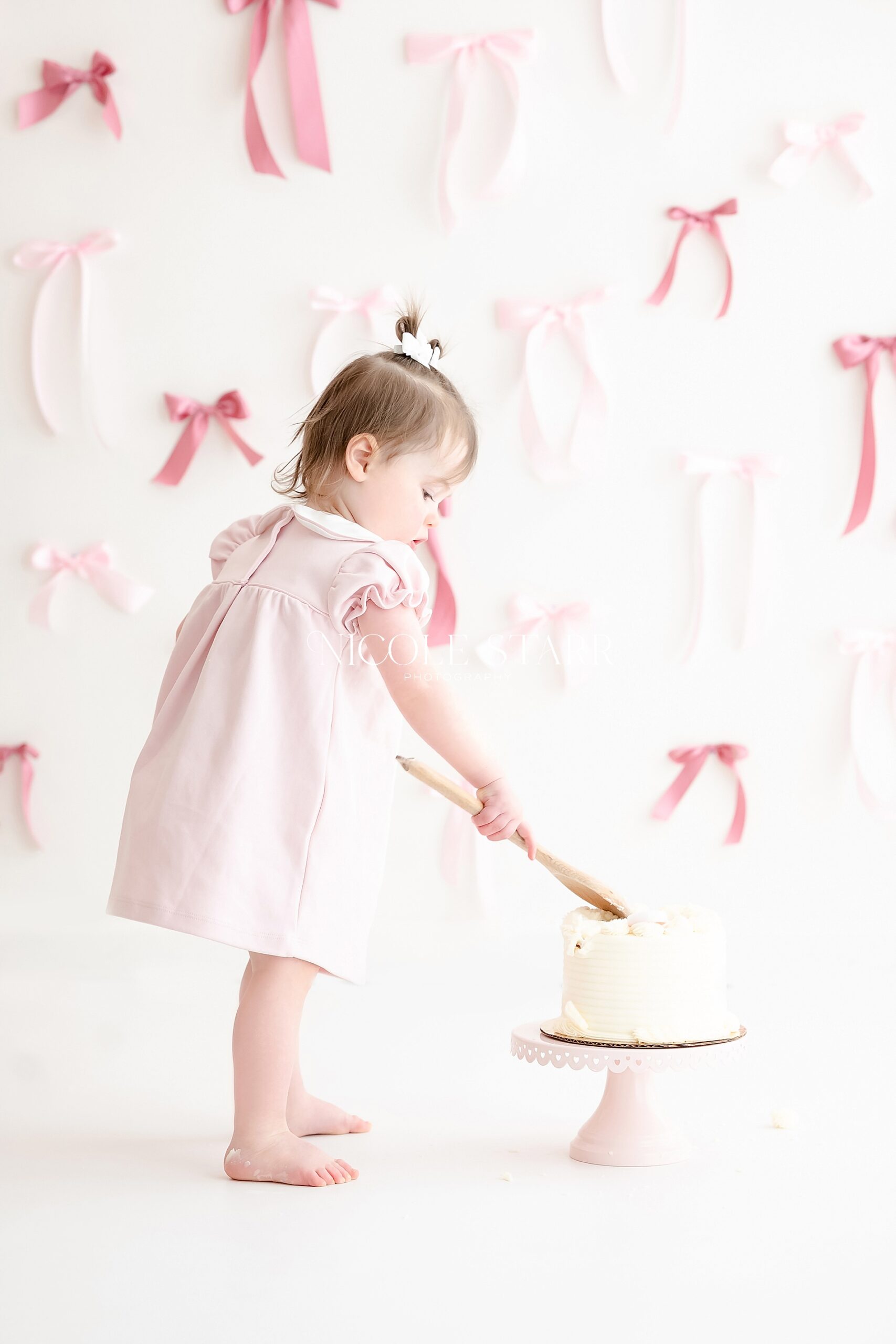 toddler girl pokes her birthday cake