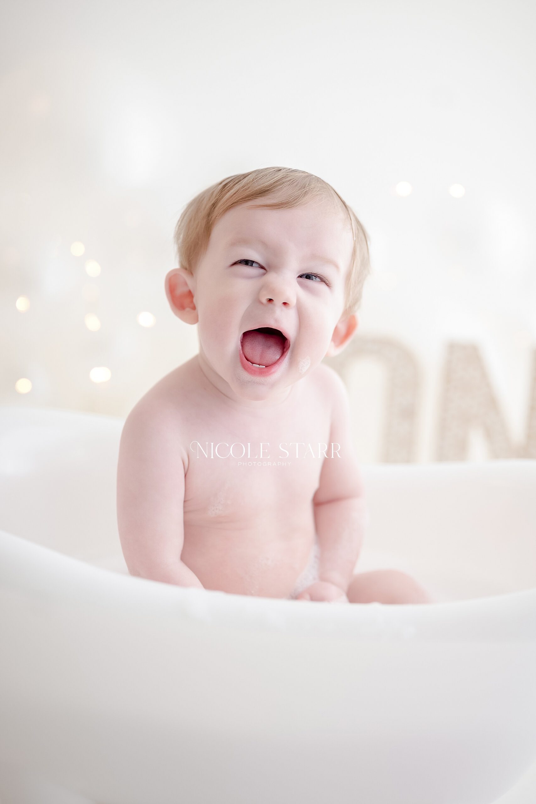 little boy smiles and laughs in bathtub during one-year milestone session