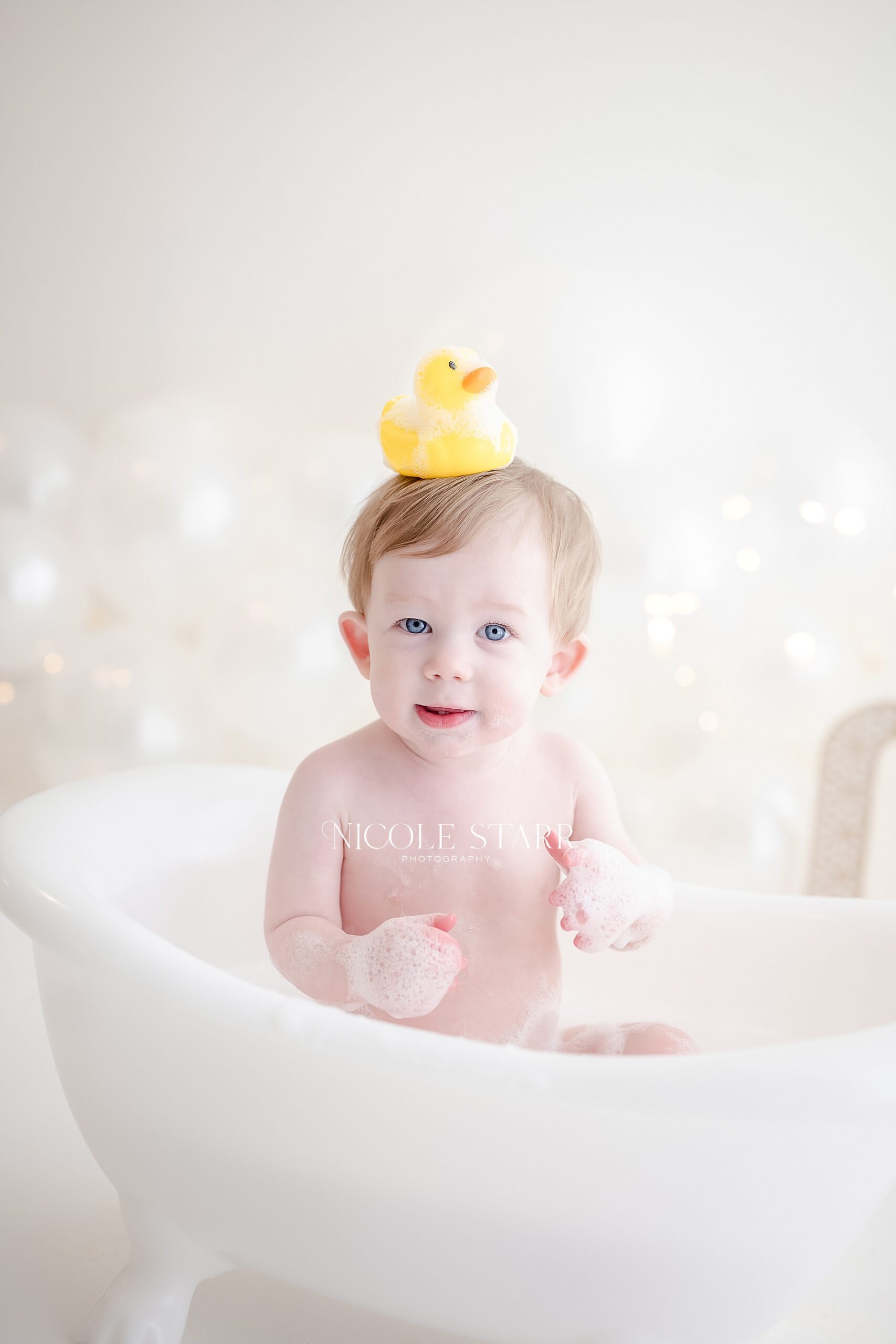 first year milestone session with little boy in bathtub after cake smash with rubber duck on his head