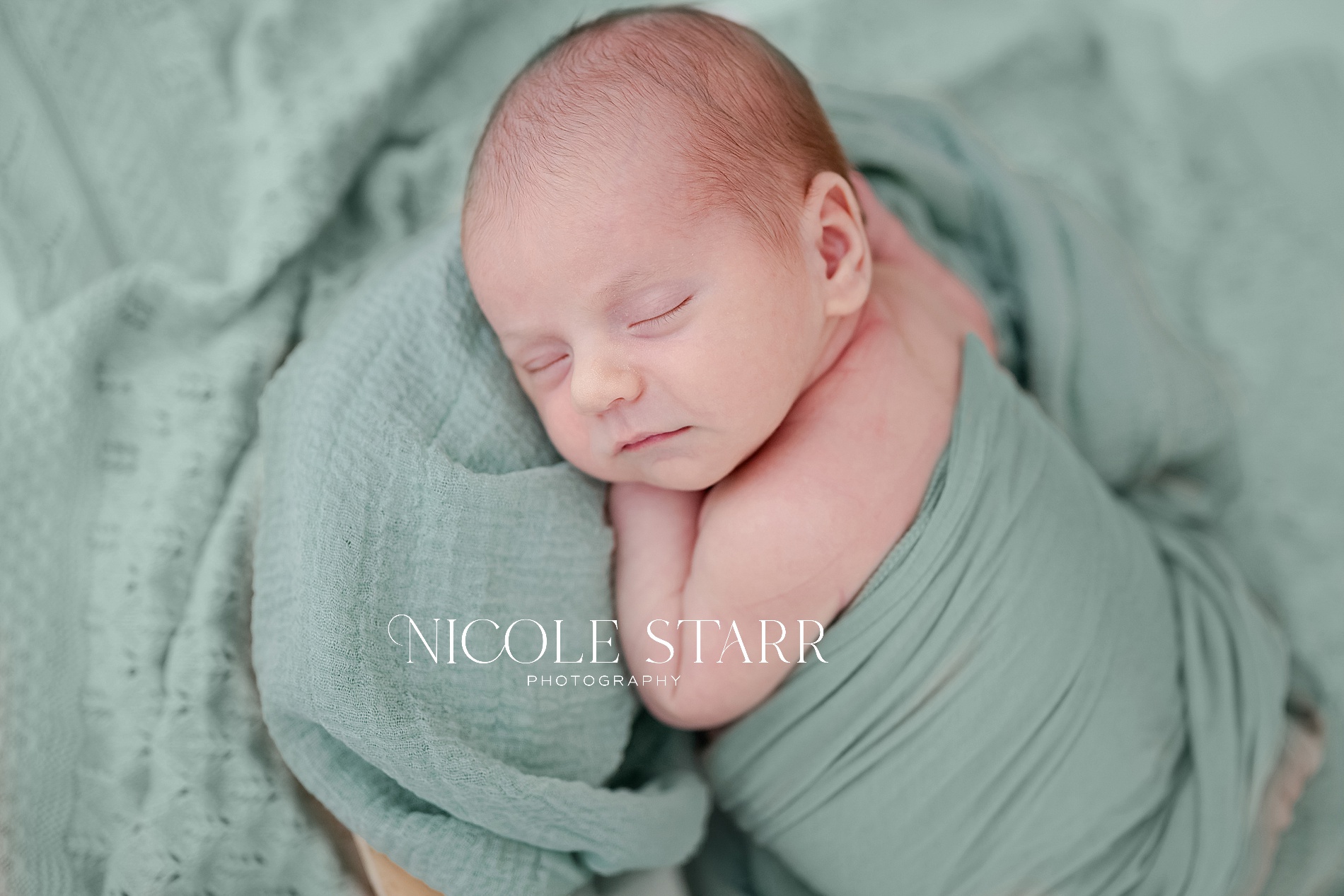 soft green blanket surrounds sleeping newborn