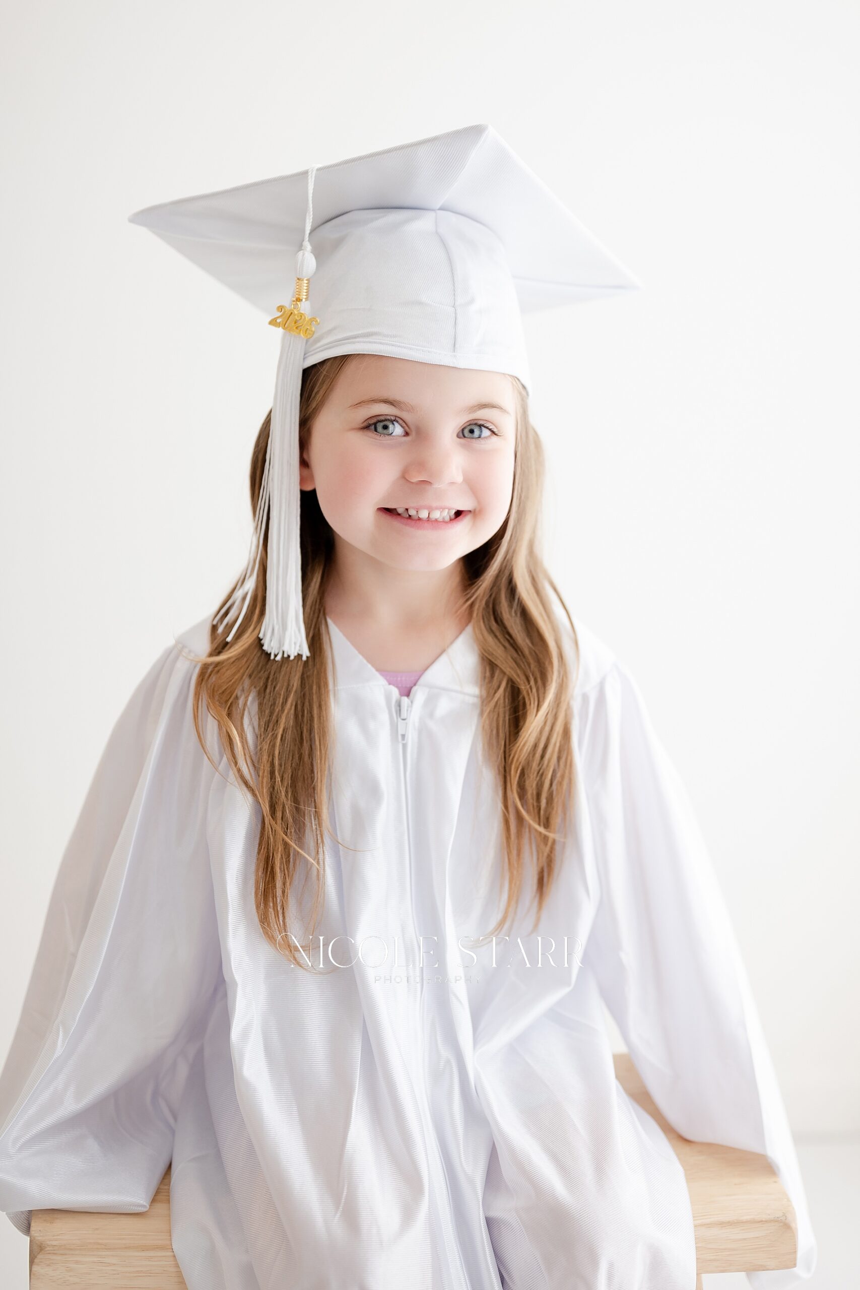 little girl in white cap and gown for tiny graduate portraits