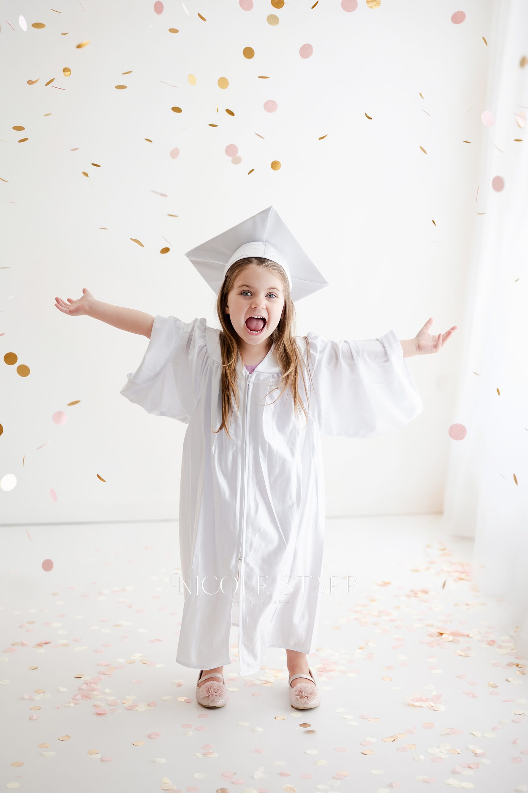 candid photos of little girl in white cap and gown for Preschool and Kindergarten Graduation Portraits