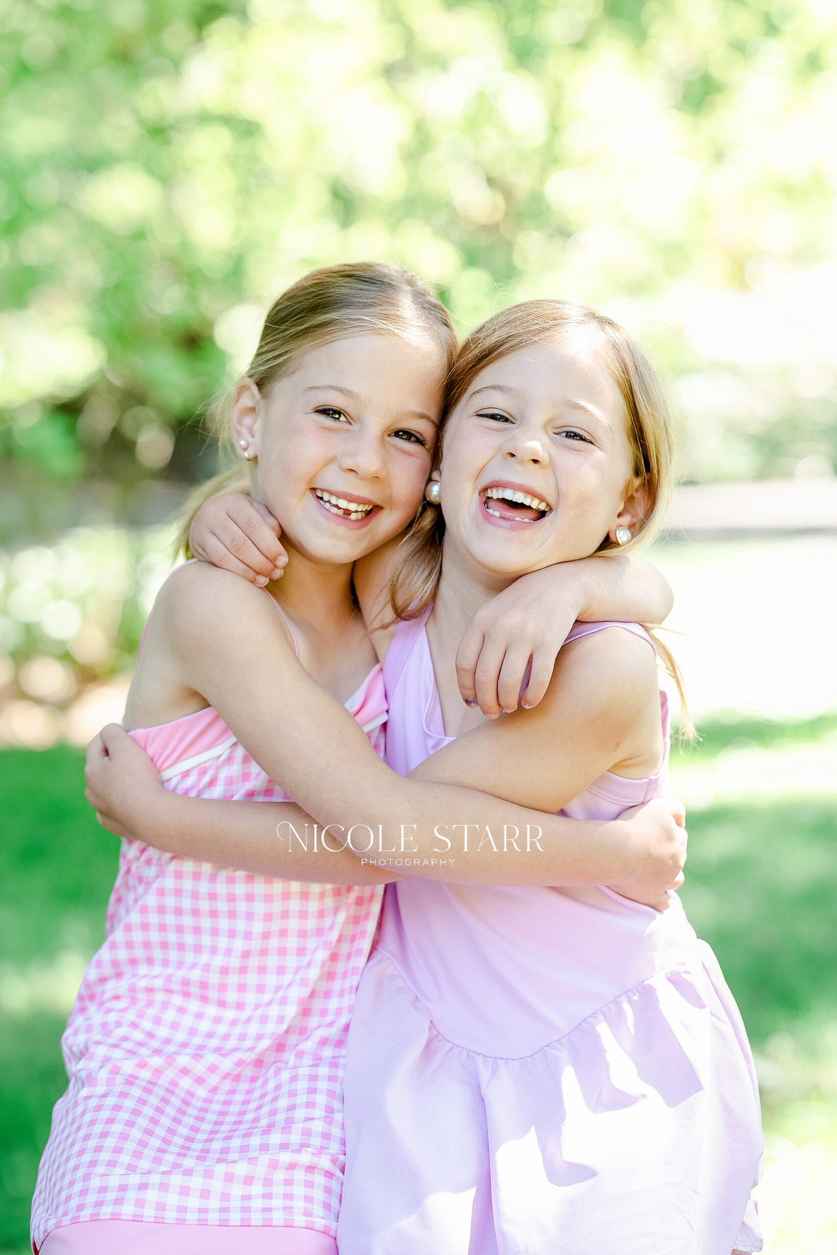 sisters hug and laugh during timeless children's portraits at Saratoga Springs studio