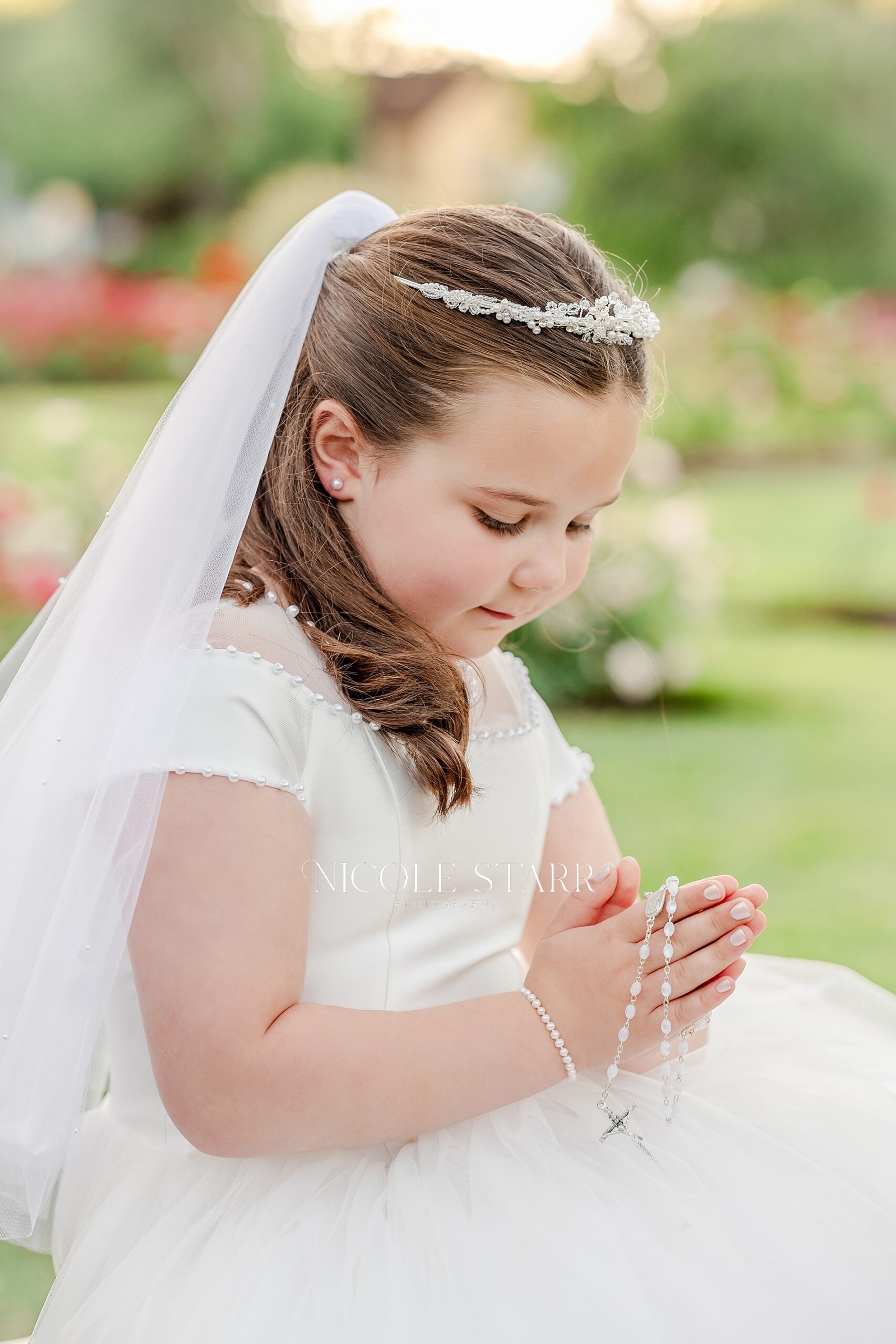 little girl in white dress holds rosary
