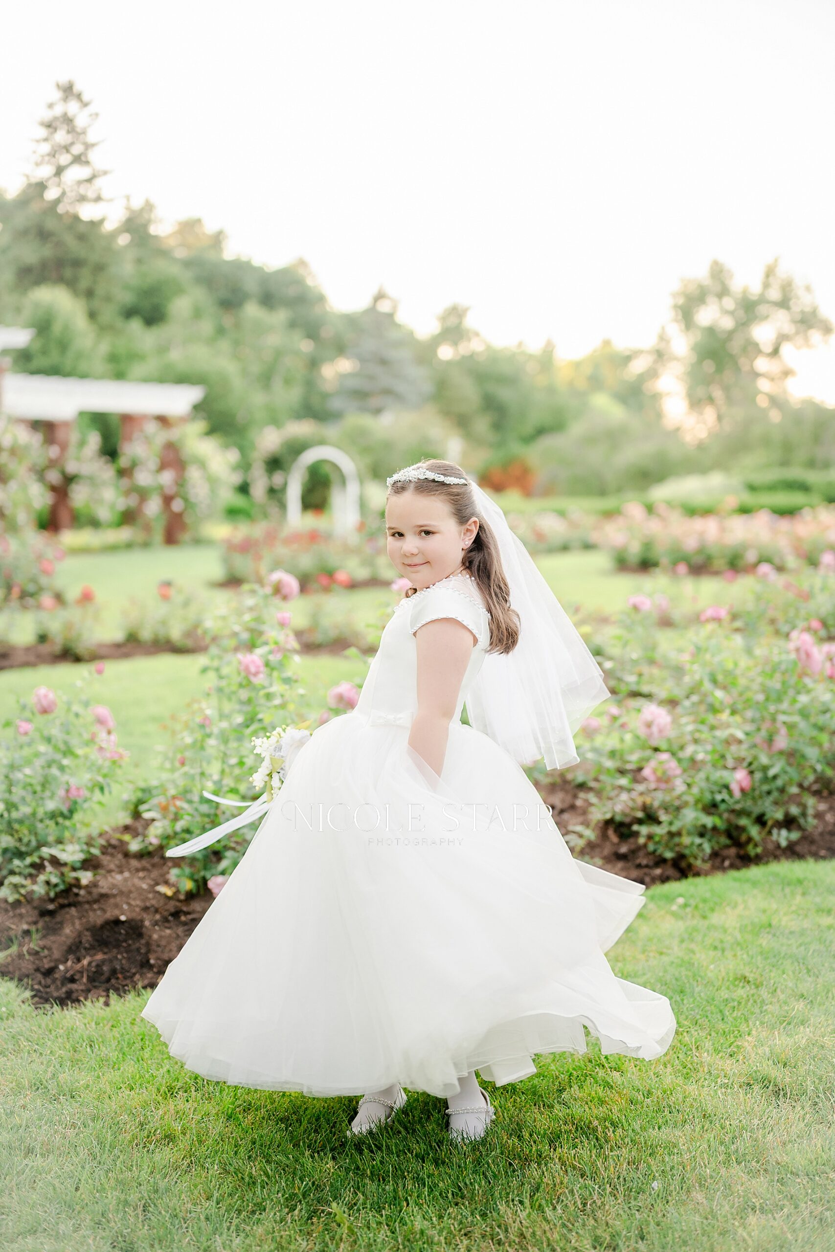 little girl twirls in first communion dress at rose garden