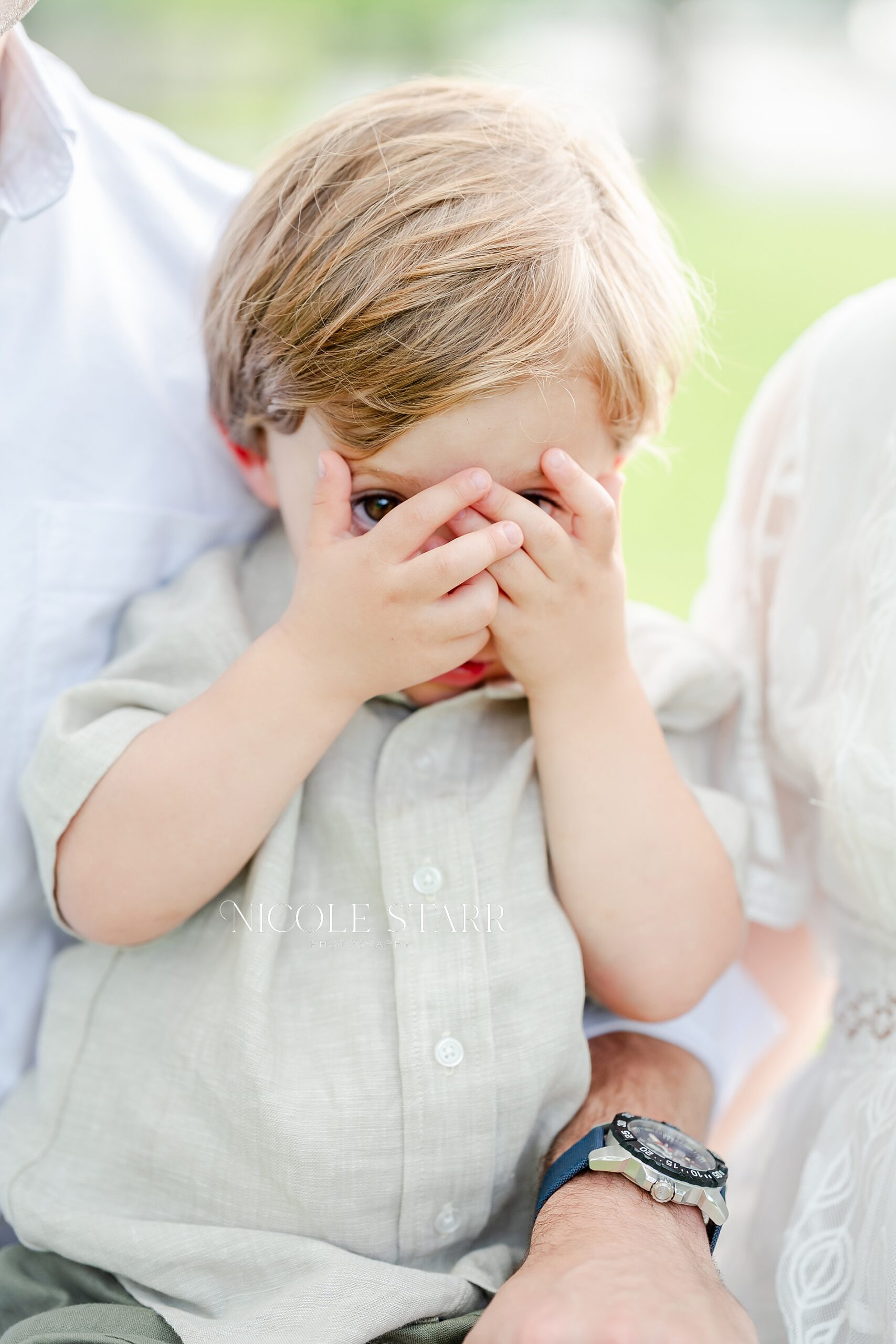 little boy covers his face with hands