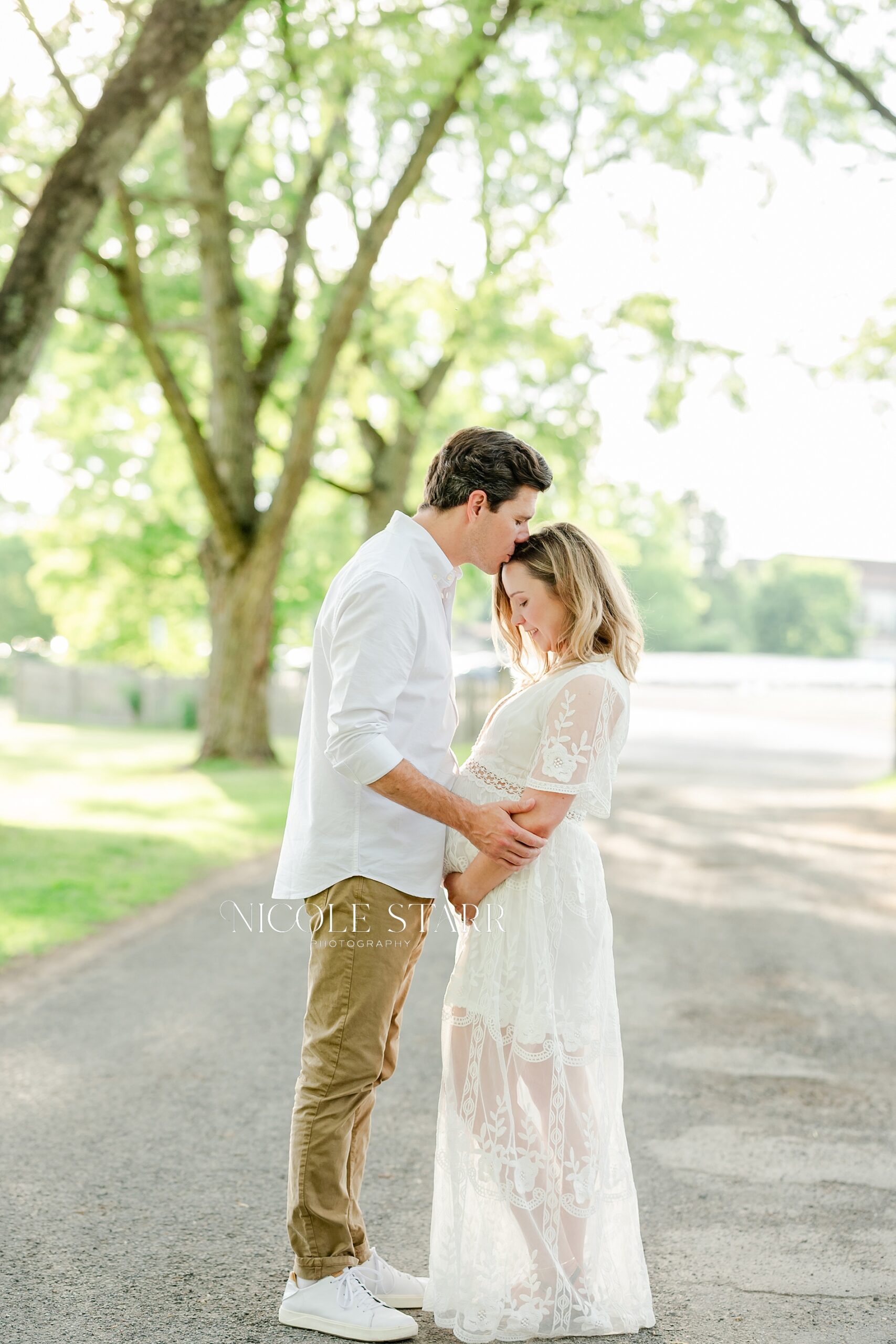 husband kisses wife's forehead during maternity session
