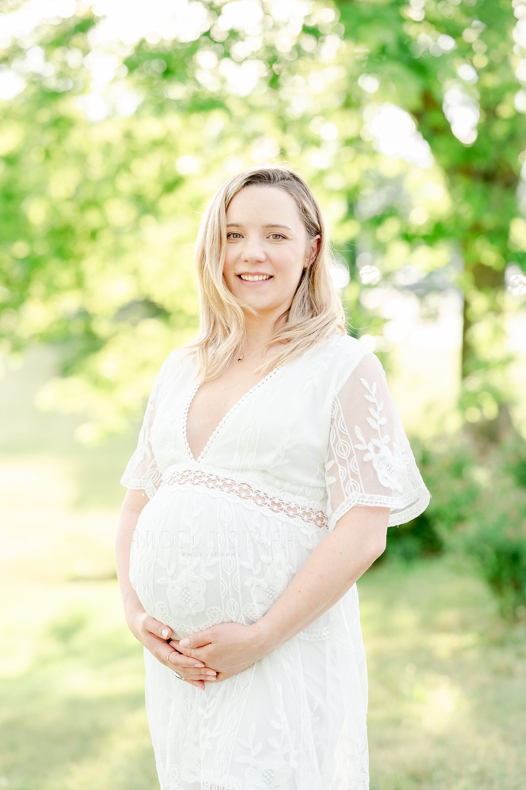 glowing mom holds her pregnant belly during golden hour