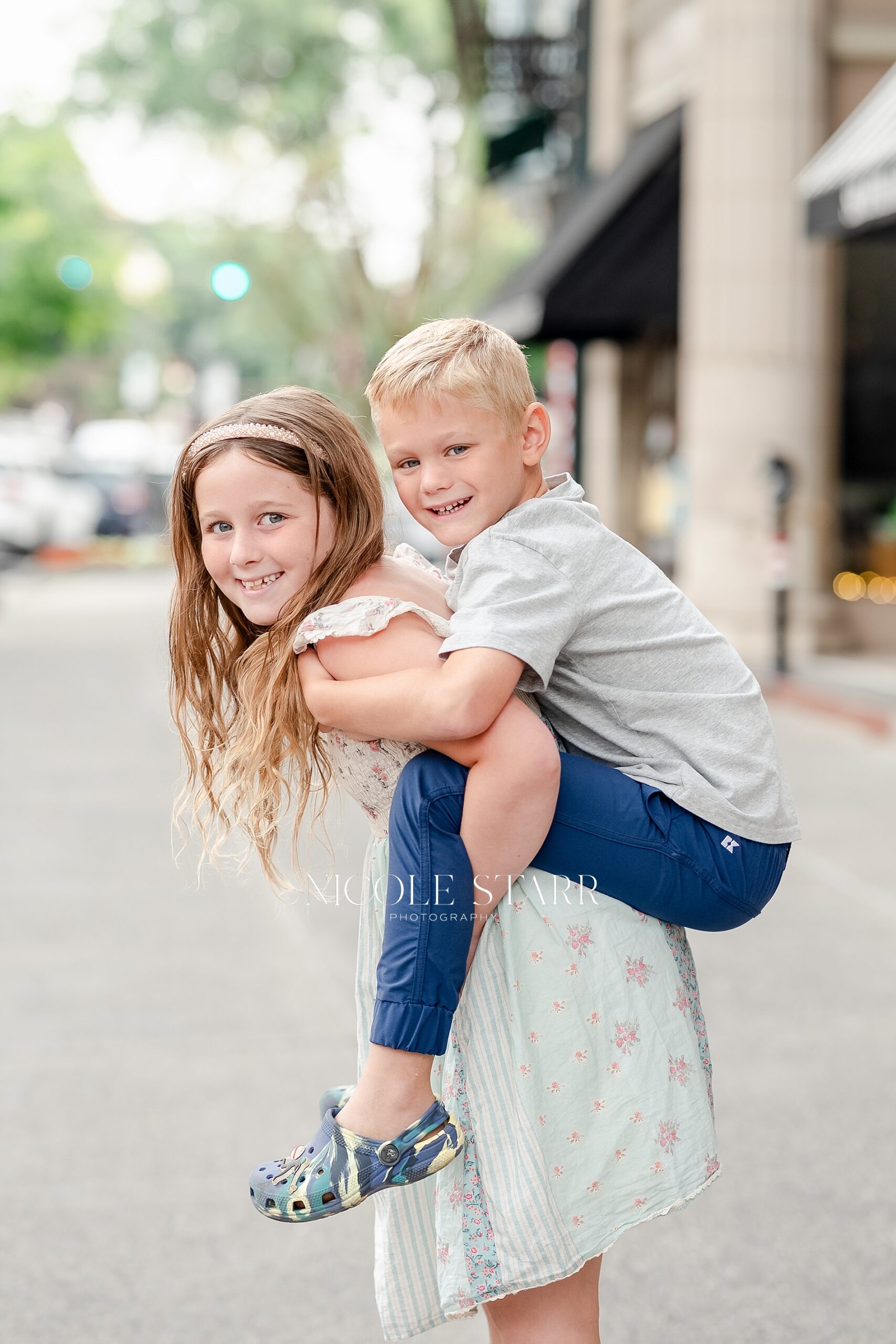 big sister carries little brother on back