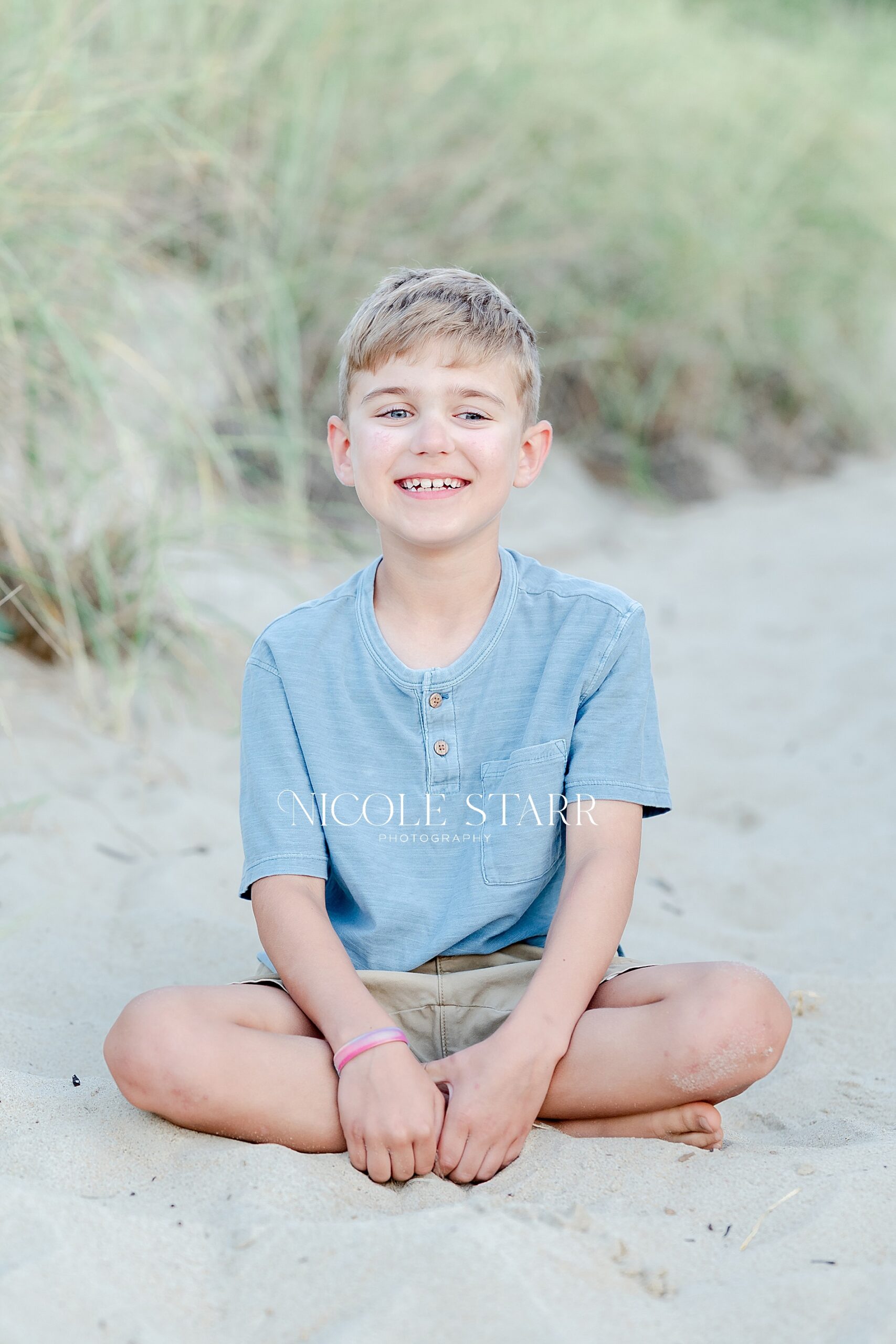boy sits in the sand at Cape Cod beach